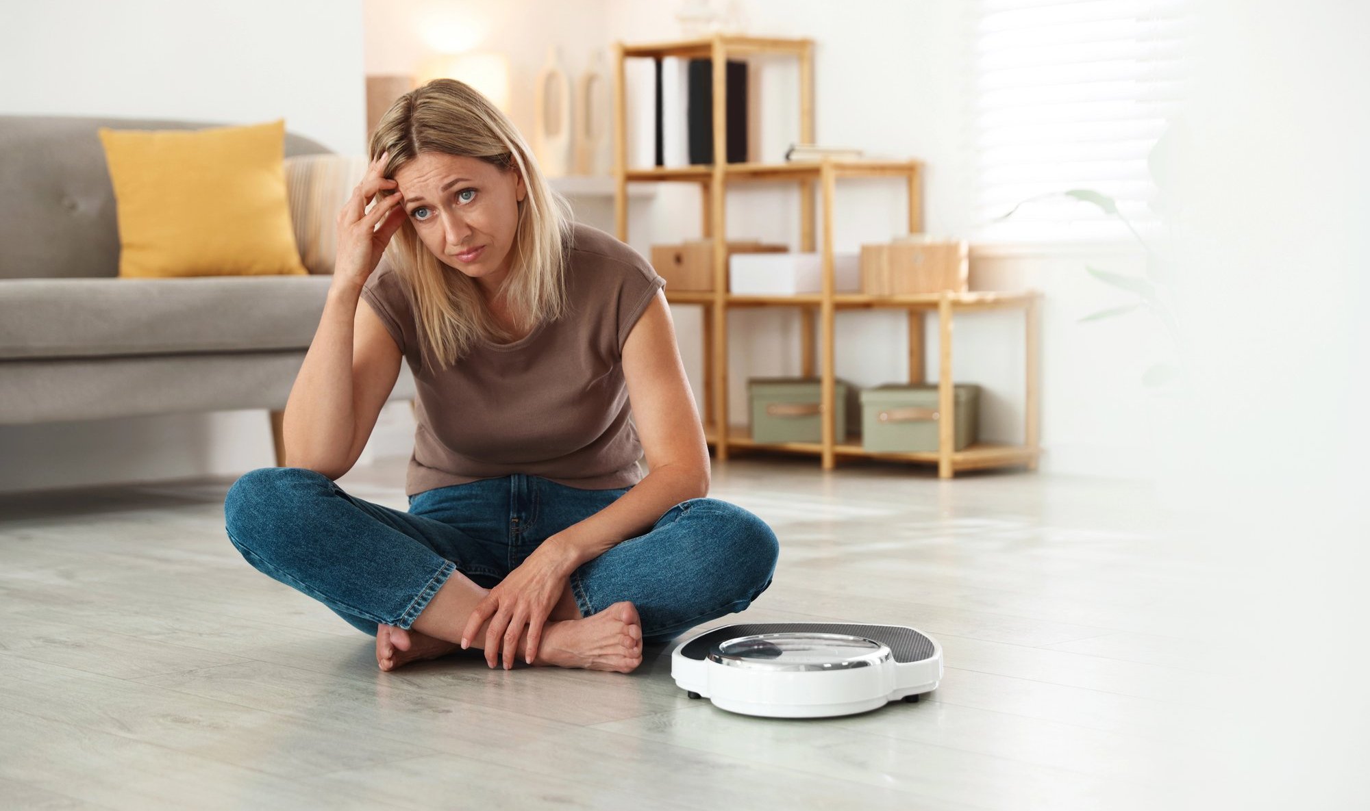  Person sitting on the floor next to a robotic vacuum cleaner in a living room.